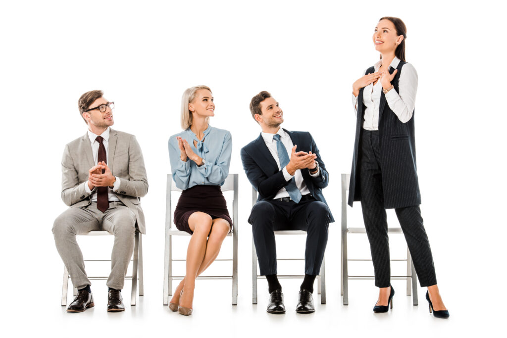 businesspeople sitting on chairs and applauding to colleague isolated on white